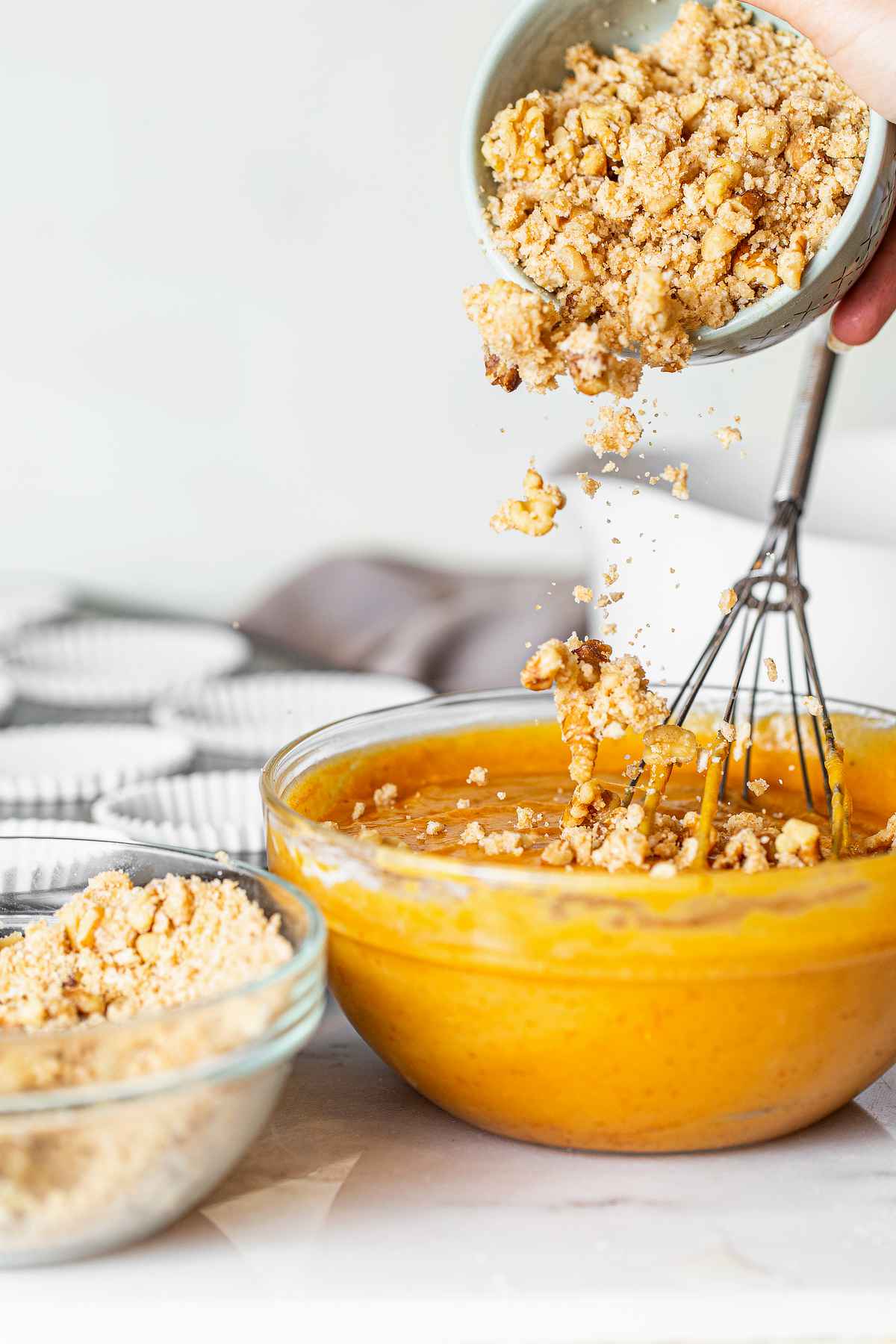 Adding pecan streusel to pumpkin muffin batter before mixing to distribute flavor throughout the muffins.