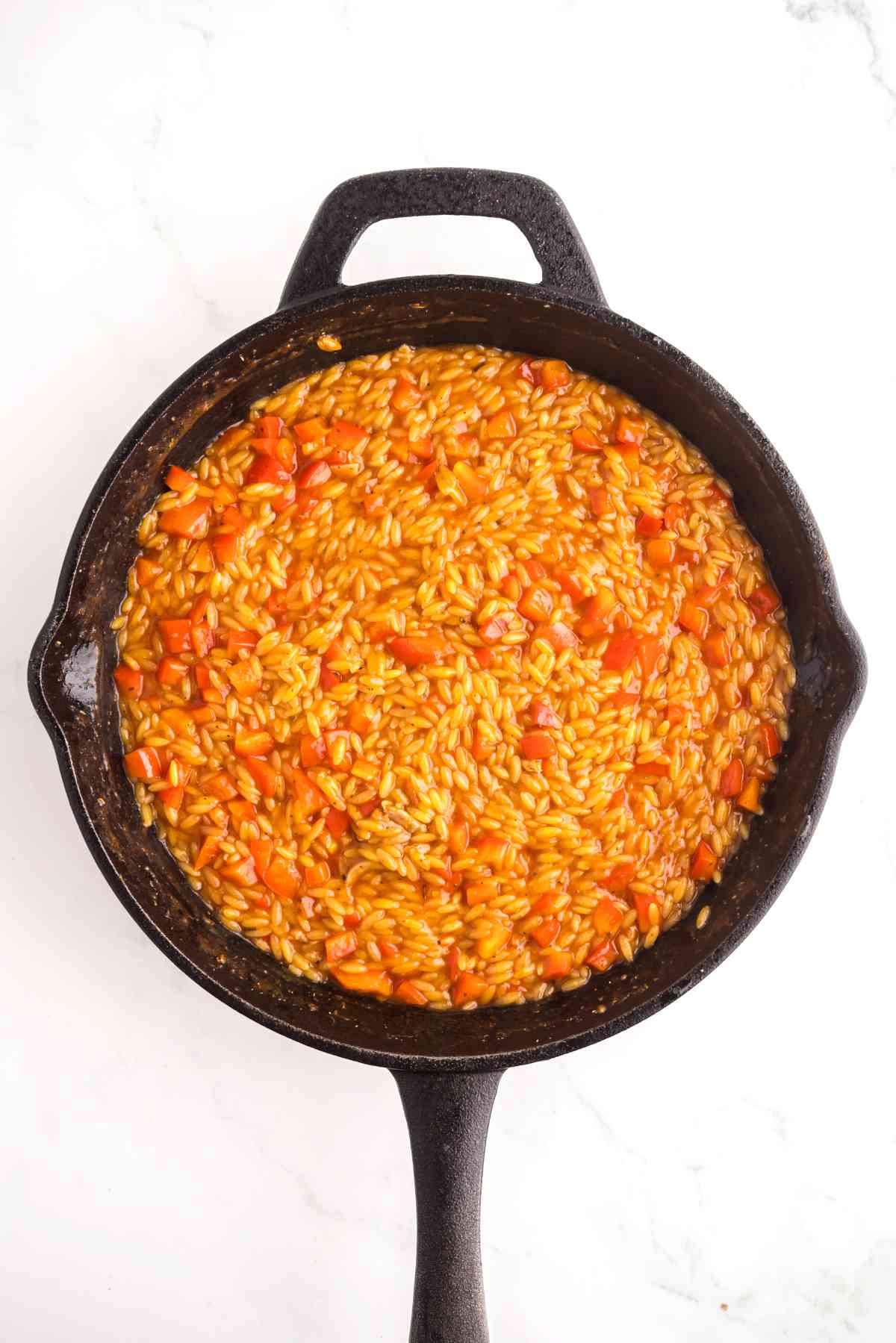 Orzo simmering with vegetables in a flavorful Cajun broth until tender and creamy.