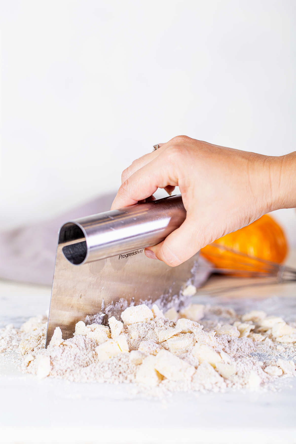 Using a pastry blender to cut cold butter into the flour mixture for pumpkin muffin streusel topping.