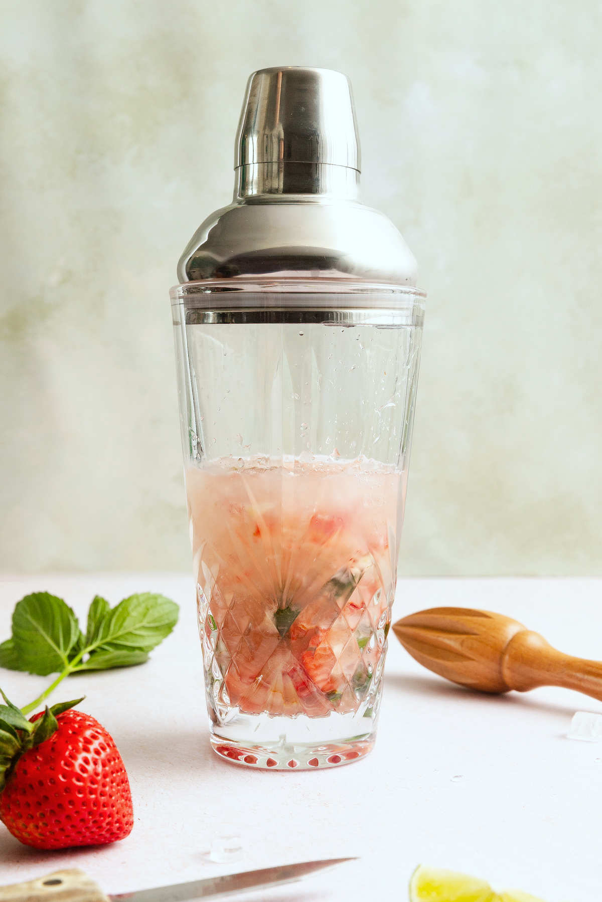 Strawberry mojito ingredients shaken with rum and ice in a cocktail shaker.