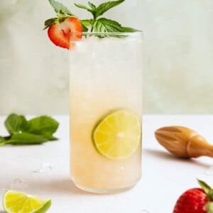 Strawberry mojito cocktail garnished with fresh mint and a sliced strawberry in a tall glass.