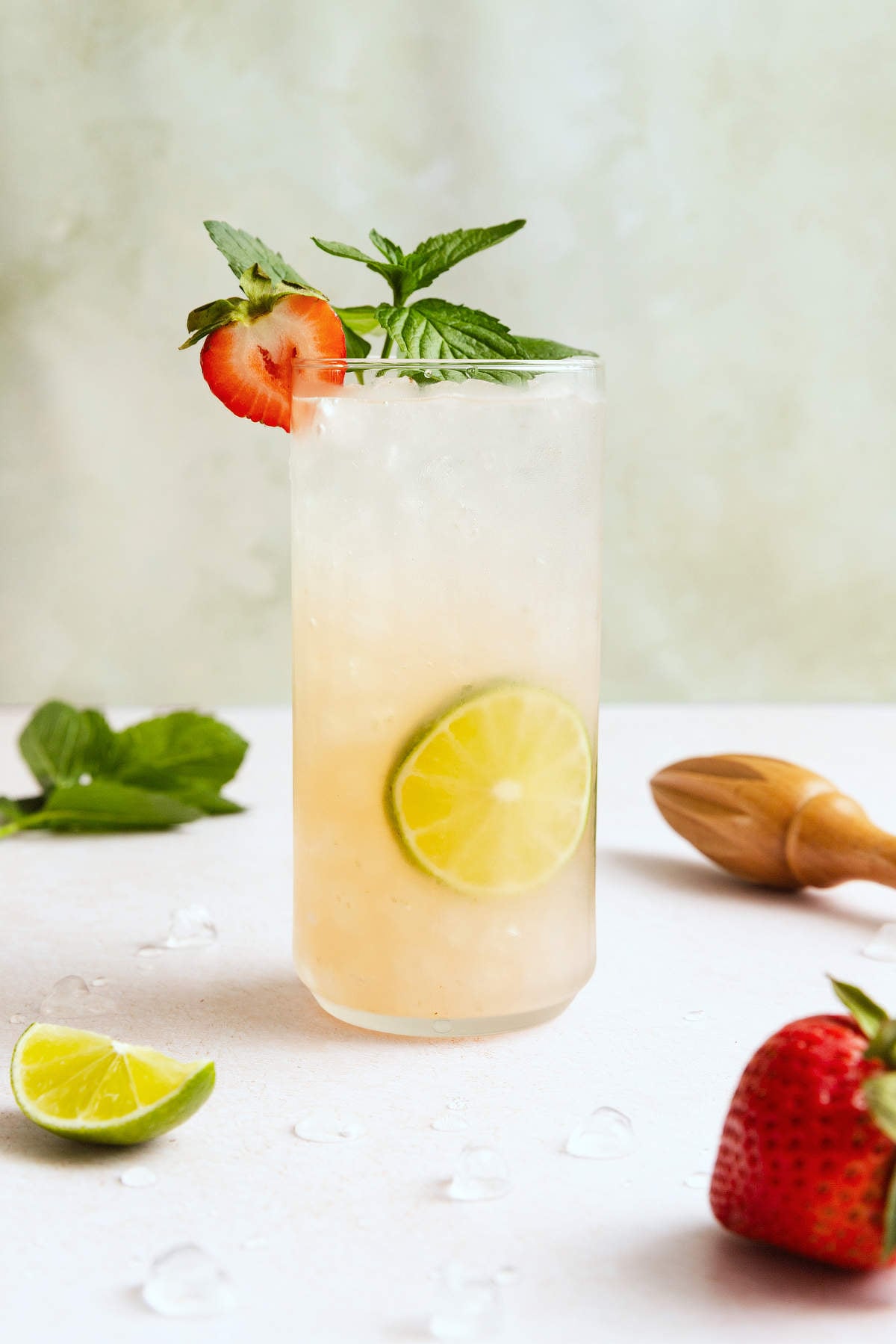 Strawberry mojito cocktail garnished with fresh mint and a sliced strawberry in a tall glass.