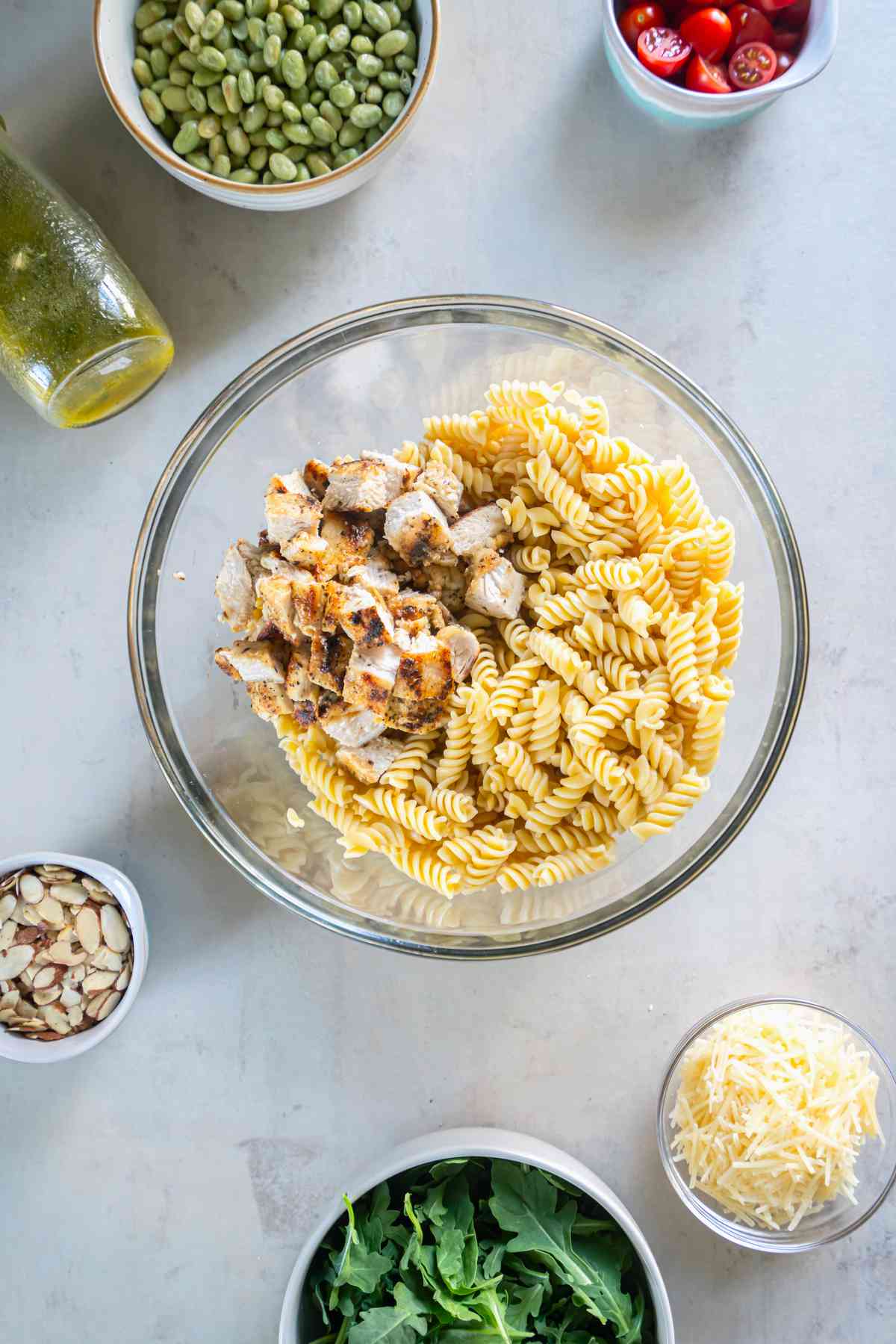 Chopped lemon pepper chicken added to cooked rotini in a large mixing bowl.