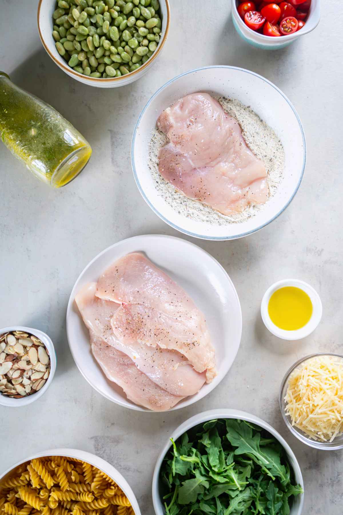 Thin chicken cutlets being coated in seasoned flour for lemon basil chicken pasta salad.