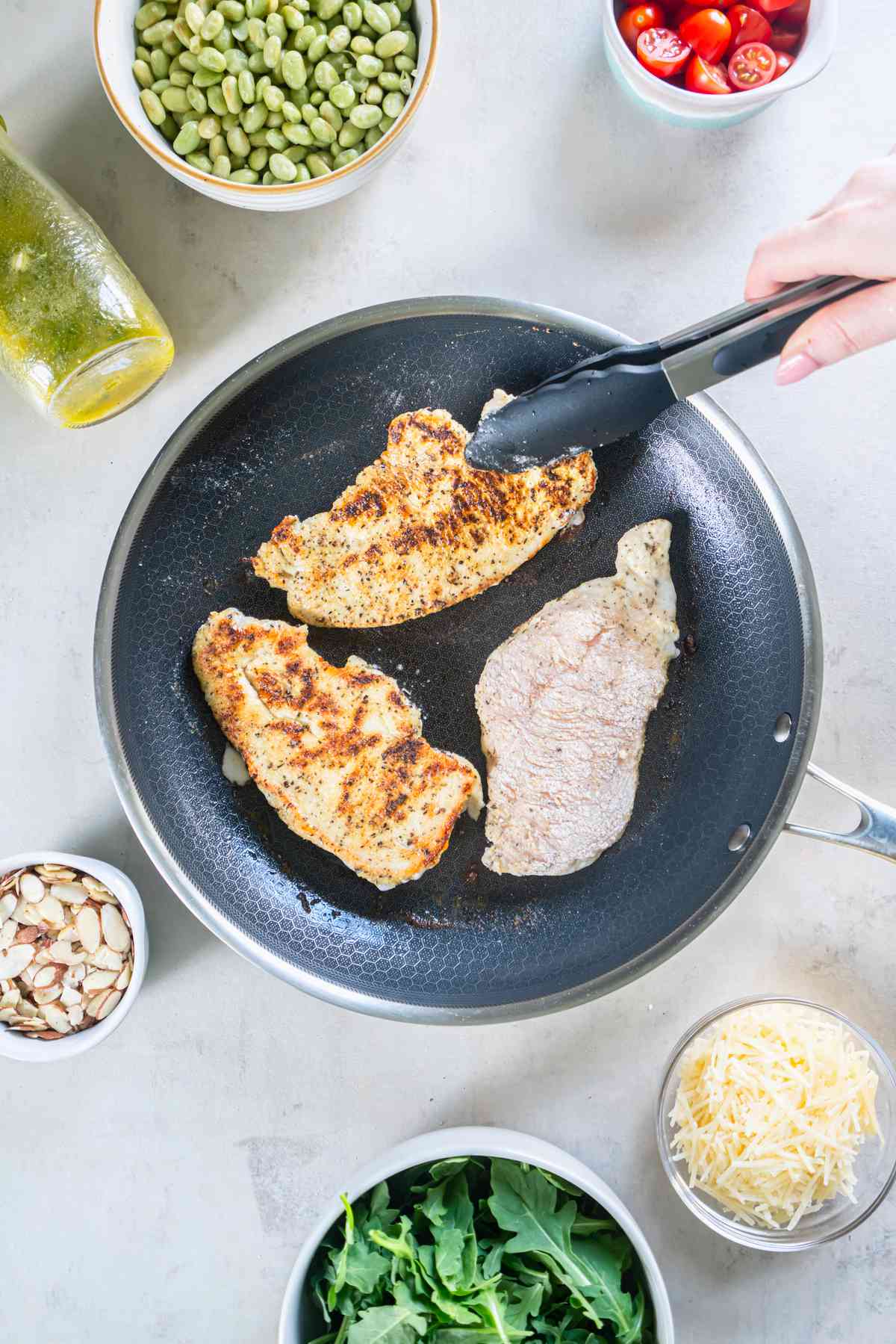 Lemon pepper chicken cutlets cooking in a skillet until golden brown.