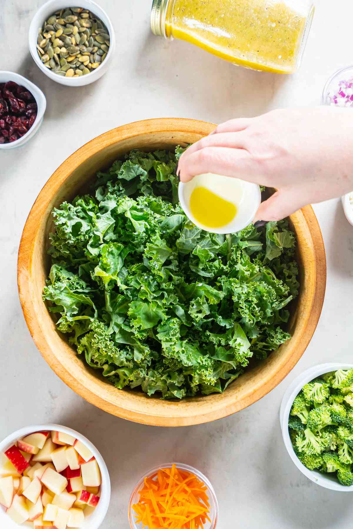 Olive oil being poured over chopped curly kale before the leaves are massaged.
