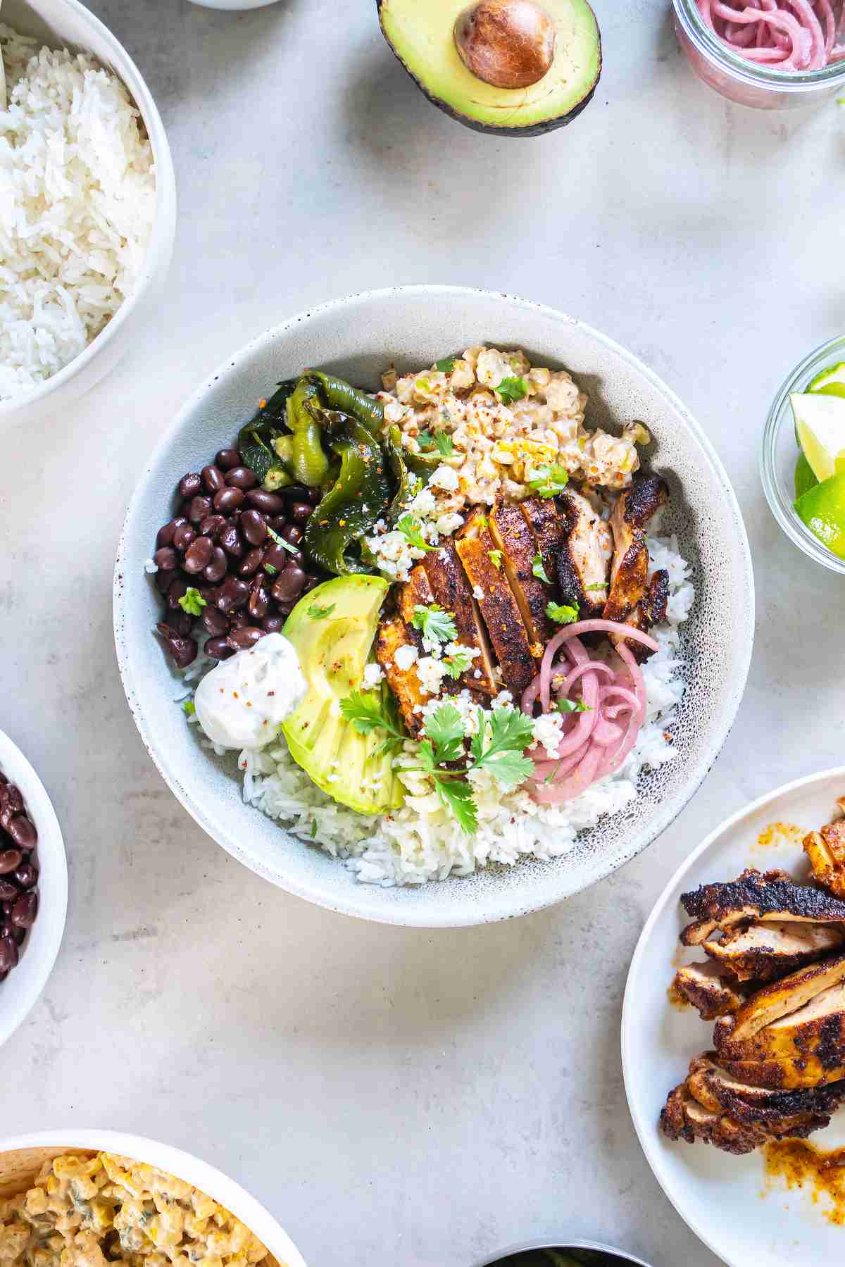 BowlRice bowl topped with sliced chili-lime chicken, creamy charred corn, black beans, avocado, pickled onions, charred green peppers, Cotija and cilantro.