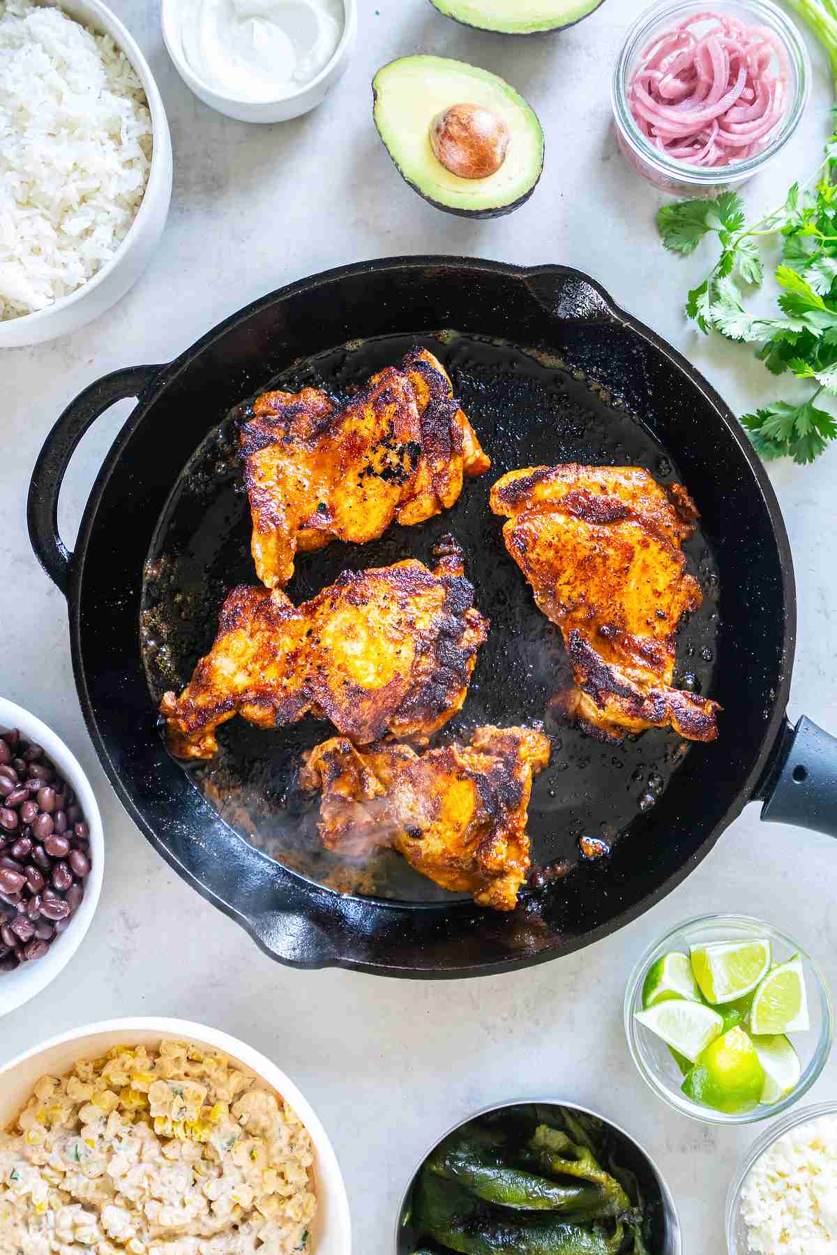 Marinated chili-lime chicken thighs browning in a cast-iron skillet.