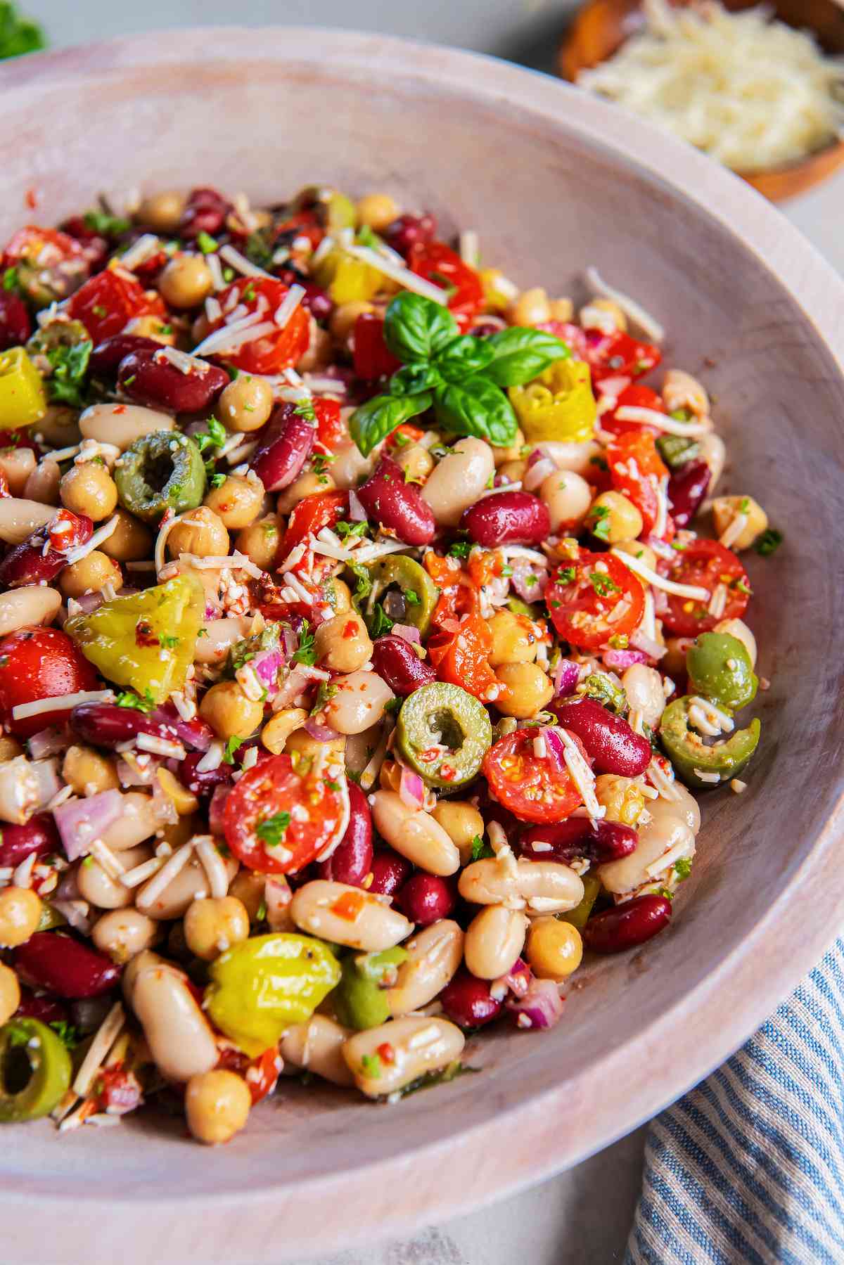 Italian three bean salad with chickpeas, cannellini beans, kidney beans, tomatoes, olives, pepperoncini, Parmesan, and fresh basil.