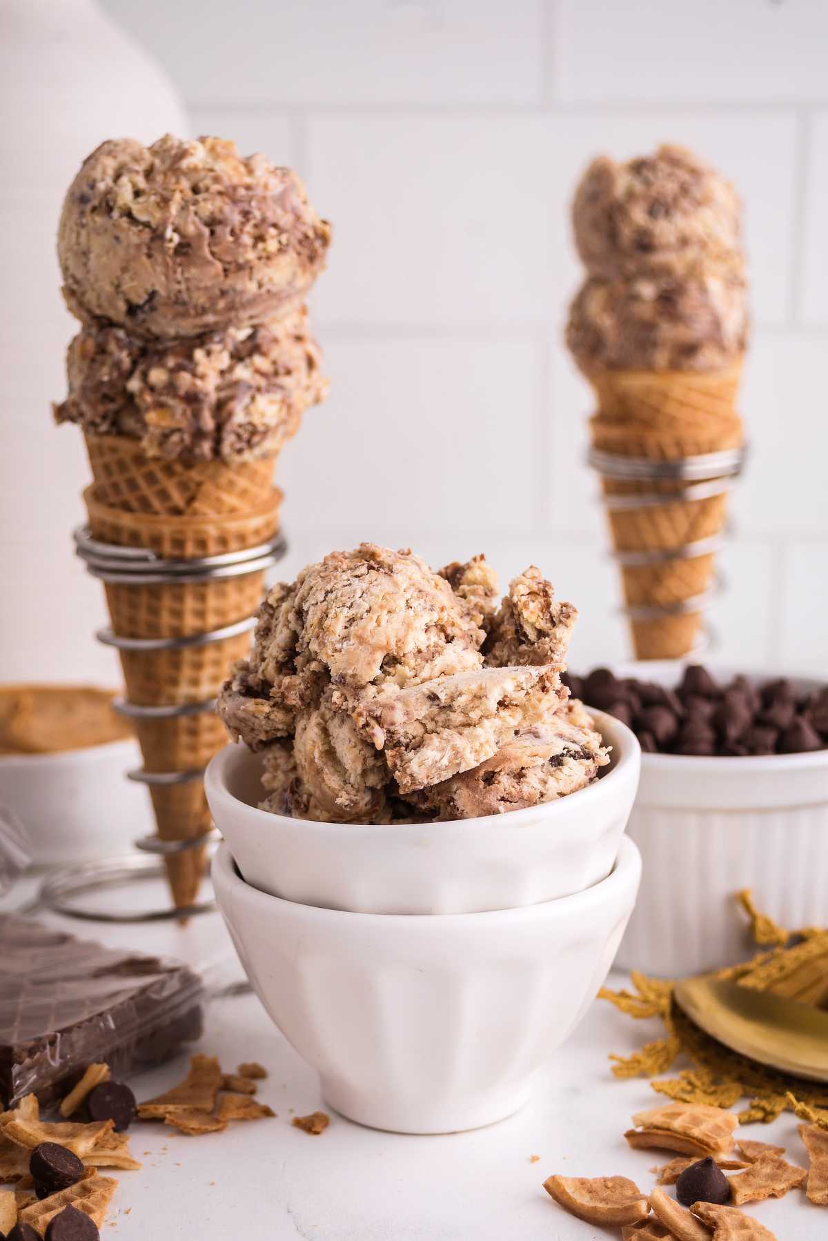 Scoops of Nutty Buddy ice cream served in bowls and waffle cones with chocolate and peanut butter mix-ins.