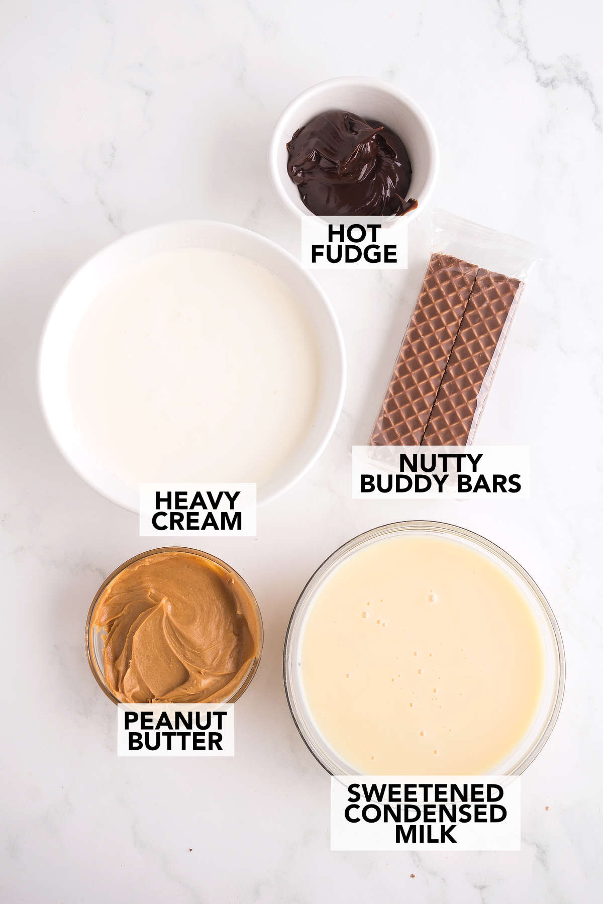 Ingredients for Nutty Buddy ice cream including heavy cream, peanut butter, sweetened condensed milk, Nutty Buddy bars and hot fudge.
