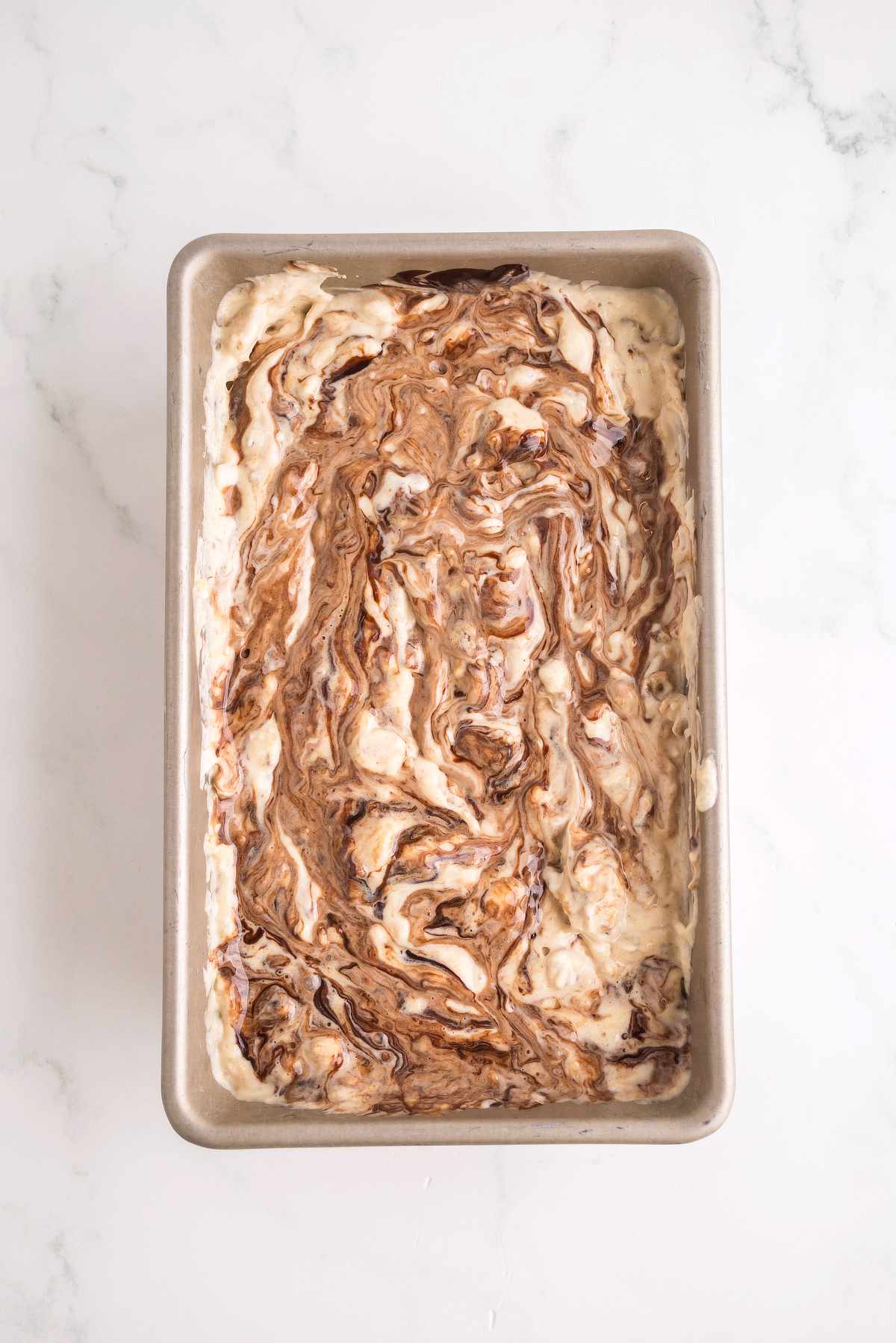 Nutty Buddy ice cream mixture in a loaf pan with hot fudge swirled throughout before freezing.