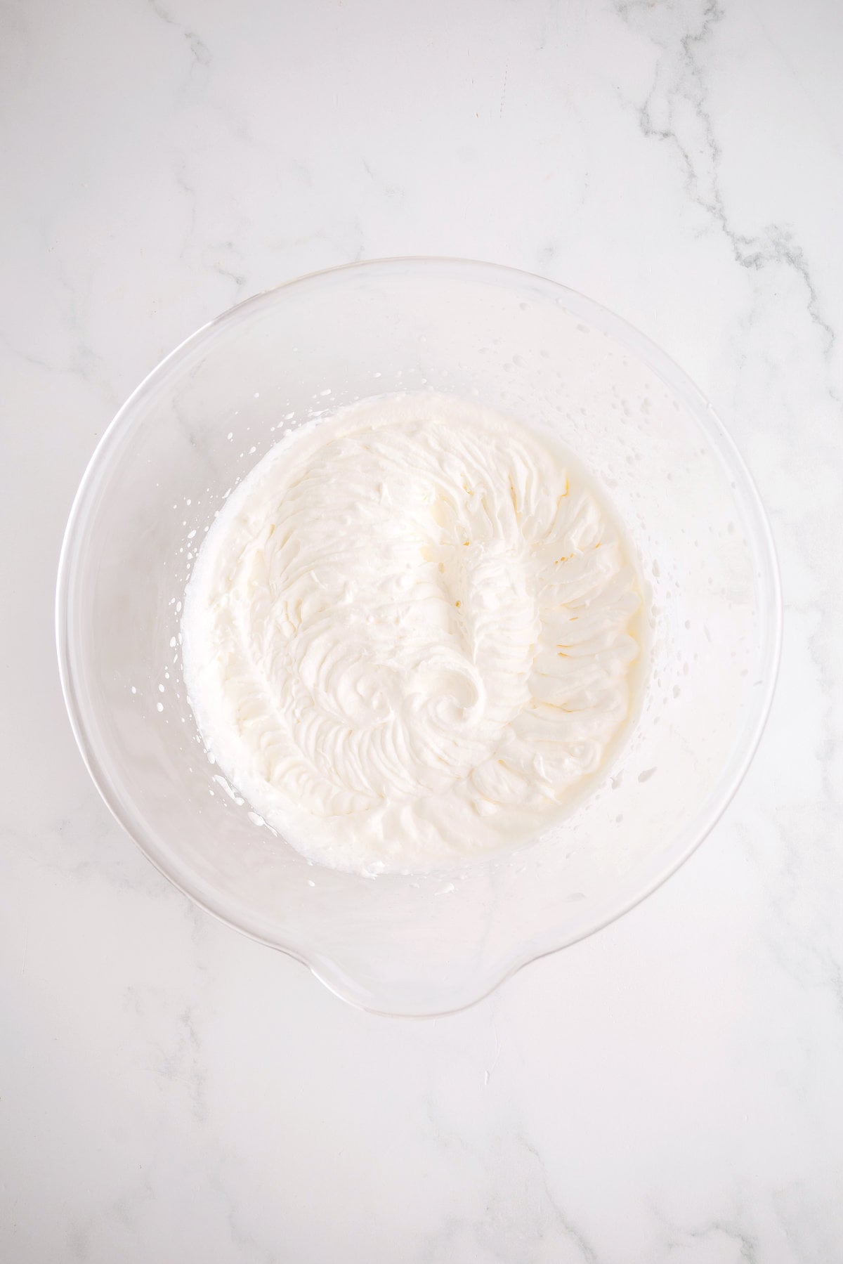 Heavy cream whipped to stiff peaks in a mixing bowl for no-churn Nutty Buddy ice cream.