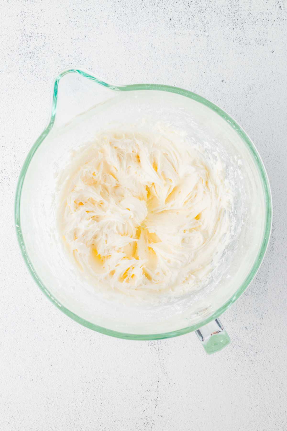 Smooth and fluffy vanilla cream cheese frosting in a glass mixing bowl