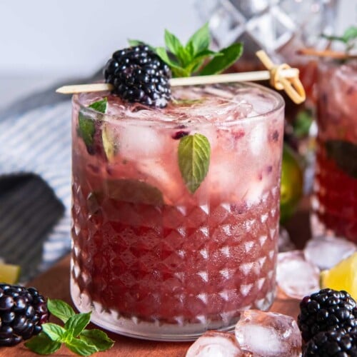 Blackberry bourbon smash in a chilled rocks glass, with crushed berries beneath the ice and a mint and blackberry garnish.