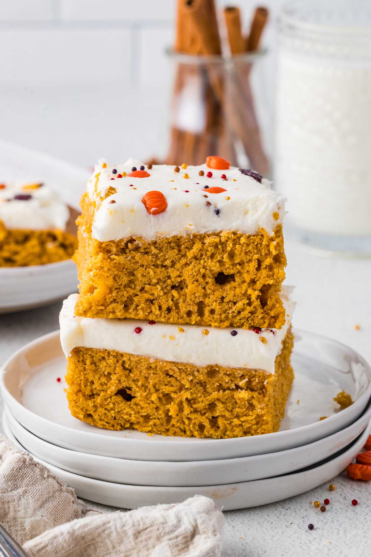 Two moist pumpkin bars stacked with thick cream cheese frosting and fall sprinkles