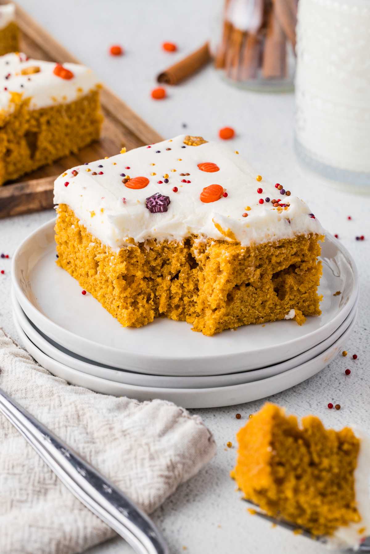 Pumpkin bar with cream cheese frosting and fall sprinkles served on a white plate