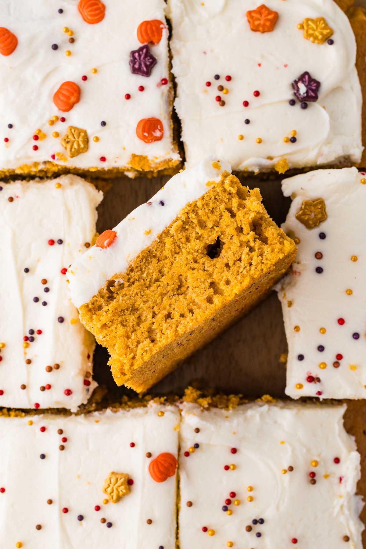 Sliced pumpkin bars with cream cheese frosting and colorful fall sprinkles