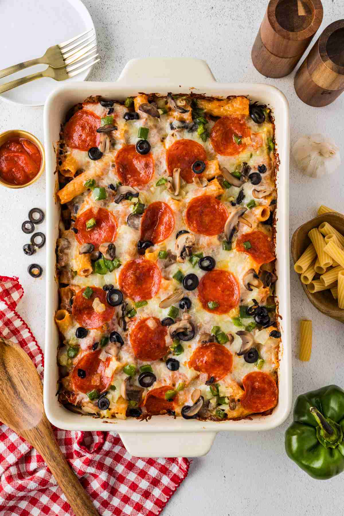 Overhead view of baked pizza casserole with melted cheese, pepperoni, mushrooms, black olives, and green peppers.