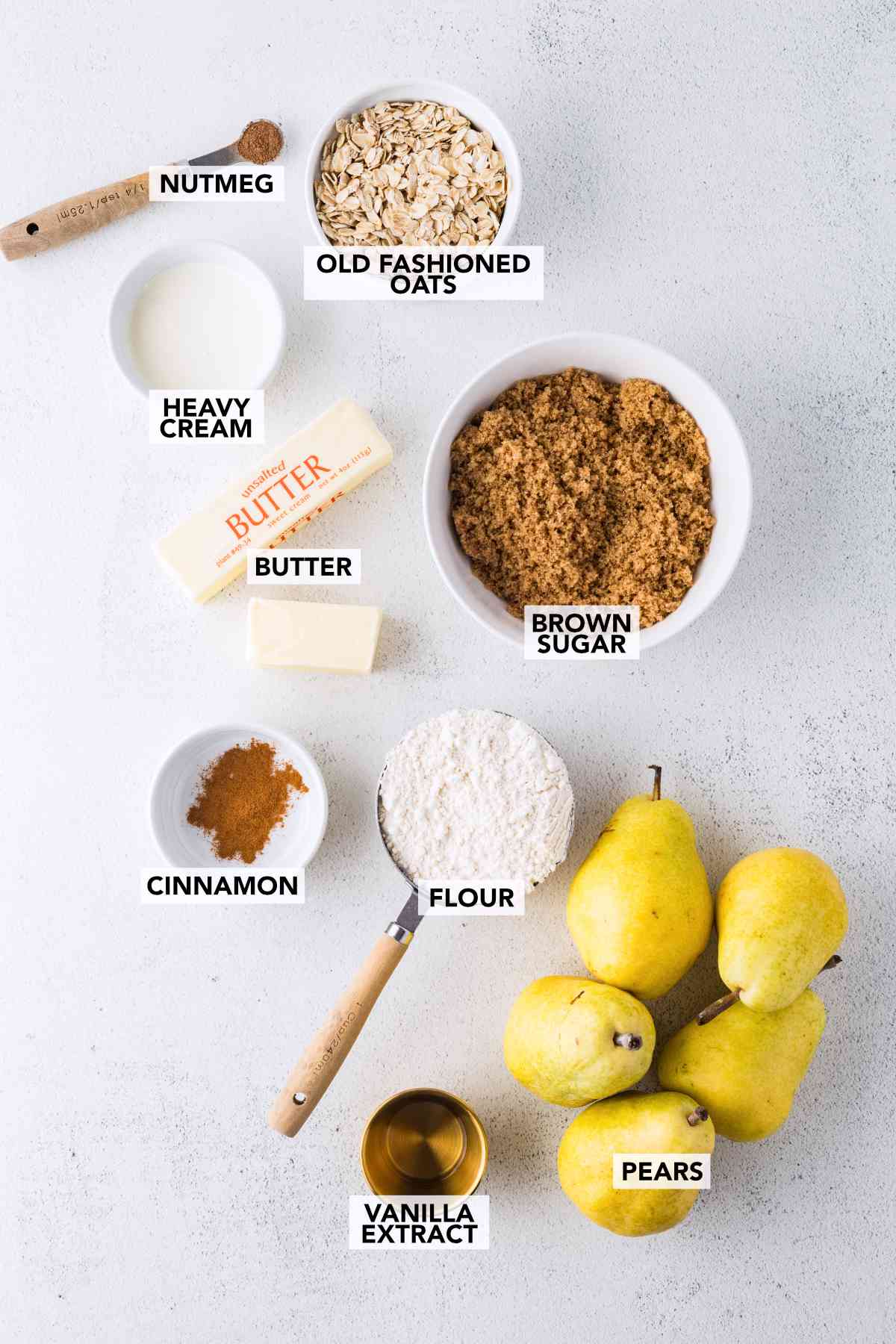 Labeled ingredients for pear crisp and caramel sauce: pears, oats, flour, brown sugar, butter, cinnamon, nutmeg, heavy cream and vanilla extract.